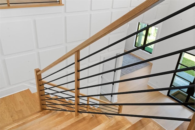 stairs with wood finished floors and a decorative wall