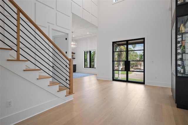 entrance foyer with stairs, plenty of natural light, baseboards, and light wood-style floors