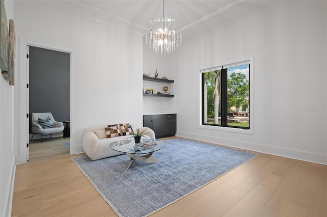 sitting room with baseboards, a towering ceiling, a chandelier, and light wood-style flooring