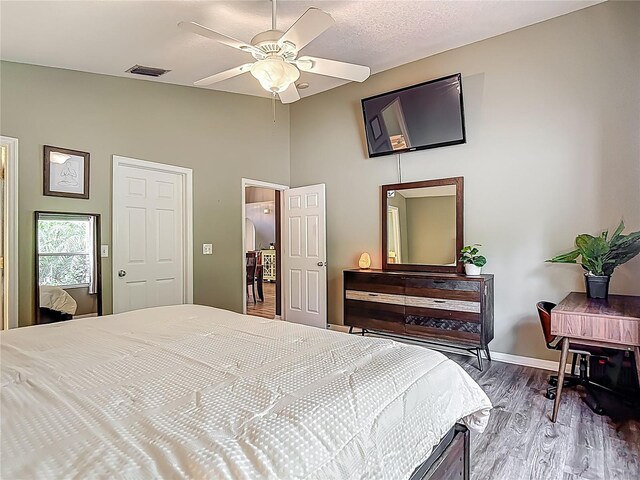 bedroom featuring baseboards, visible vents, a towering ceiling, wood finished floors, and ceiling fan