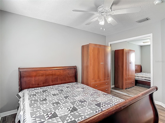 bedroom with baseboards, wood finished floors, visible vents, and a closet