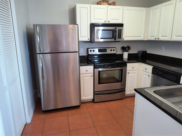kitchen with dark countertops, white cabinets, stainless steel appliances, and light tile patterned flooring