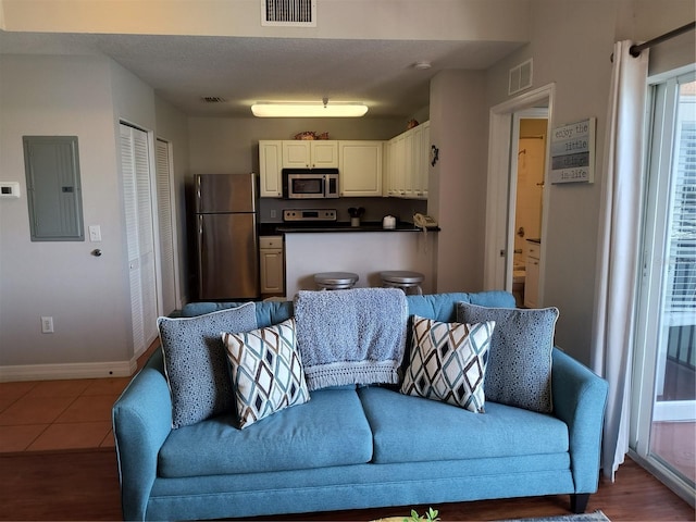 living room with baseboards, visible vents, wood finished floors, and electric panel