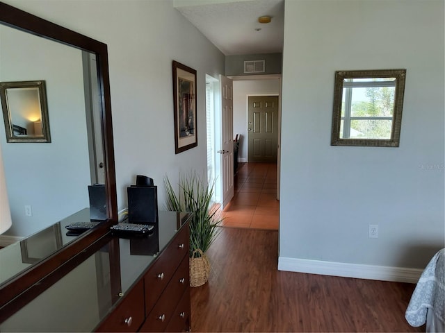 hall with baseboards, visible vents, and dark wood finished floors