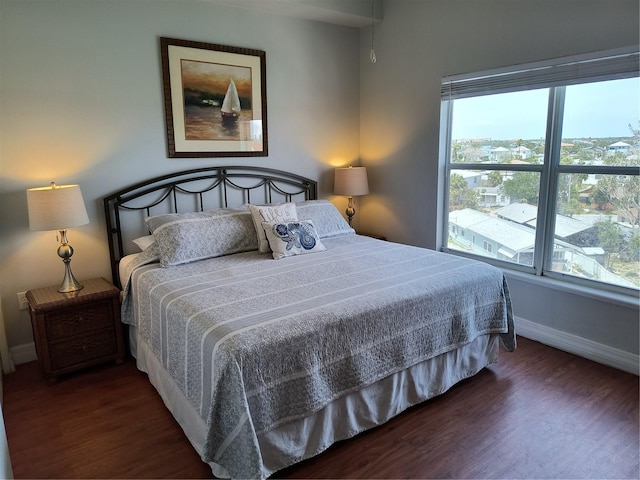 bedroom with baseboards, multiple windows, and wood finished floors