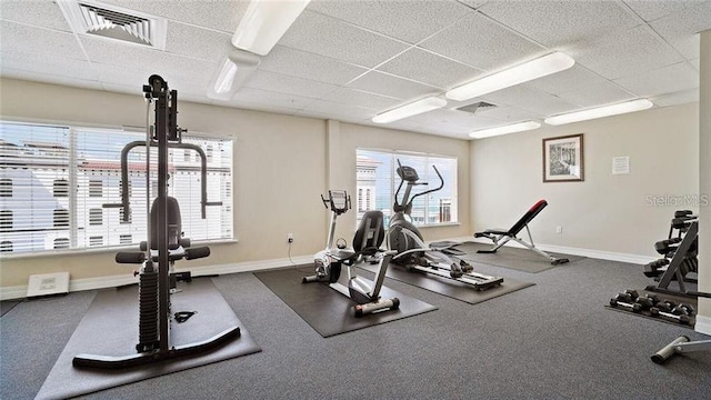 gym featuring baseboards, a drop ceiling, and visible vents