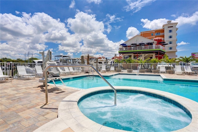 pool with fence, a community hot tub, and a patio area