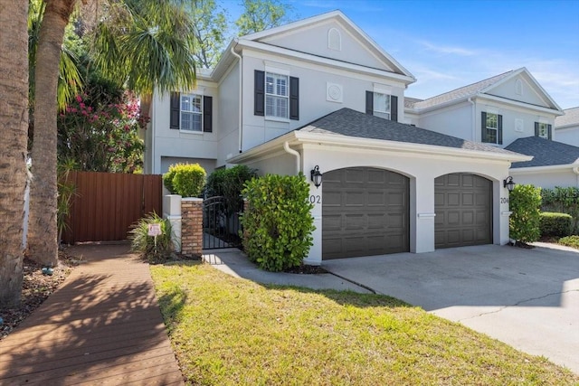 view of front facade with a garage, fence, a front yard, stucco siding, and concrete driveway