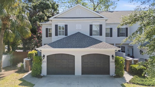 greek revival house with a garage, stucco siding, concrete driveway, and roof with shingles