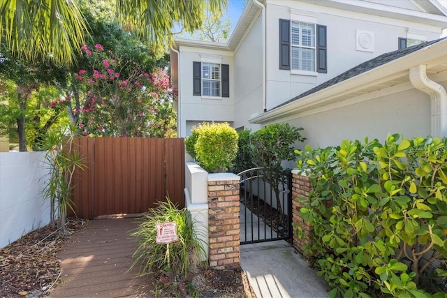 view of home's exterior with a gate, stucco siding, a deck, and fence