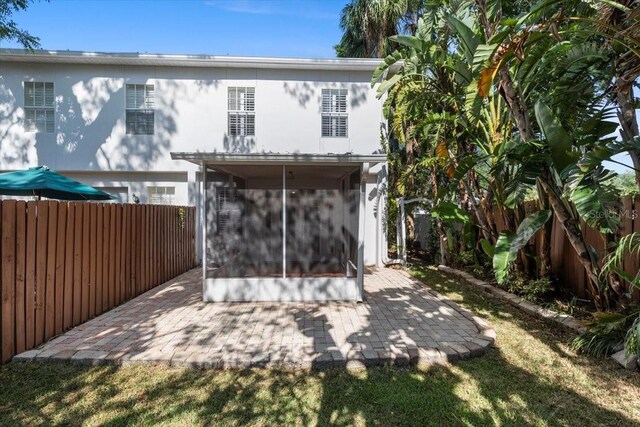 rear view of house featuring a fenced backyard, a patio, stucco siding, and a sunroom