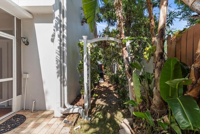 view of side of home featuring fence and stucco siding