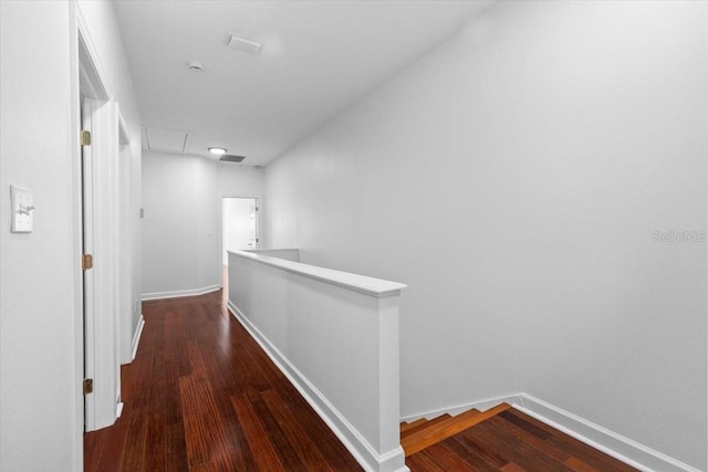 hallway featuring baseboards, wood finished floors, and an upstairs landing