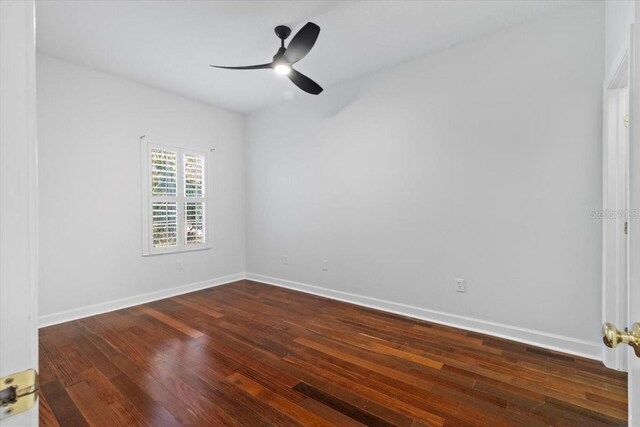empty room featuring baseboards, ceiling fan, and dark wood-style floors