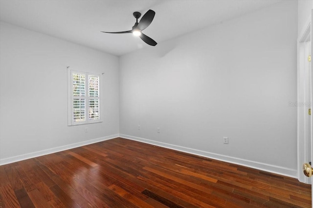 spare room with baseboards, a ceiling fan, and dark wood finished floors
