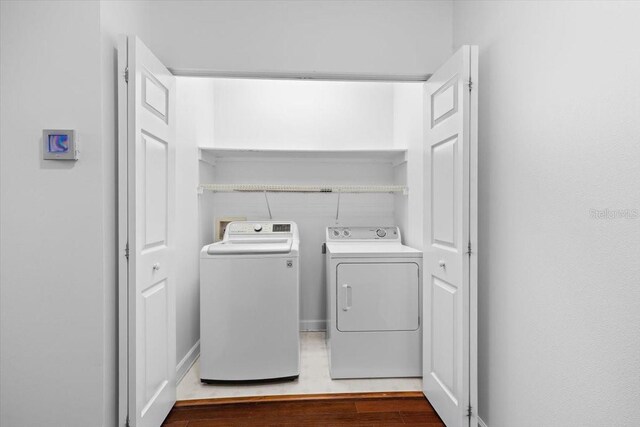 clothes washing area with laundry area, independent washer and dryer, and wood finished floors