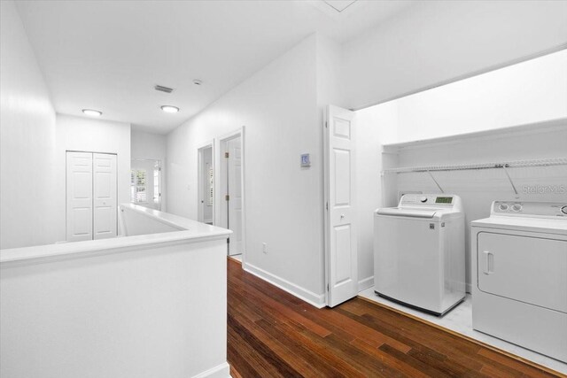washroom with washer and dryer, laundry area, baseboards, and wood finished floors