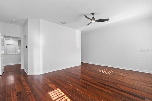 empty room featuring a ceiling fan, baseboards, visible vents, and wood finished floors