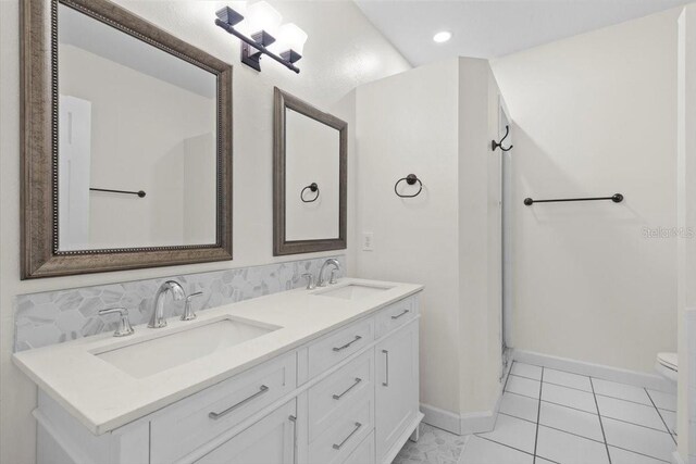 bathroom featuring tile patterned flooring, a sink, double vanity, and toilet