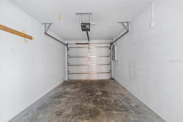 garage featuring a garage door opener and concrete block wall