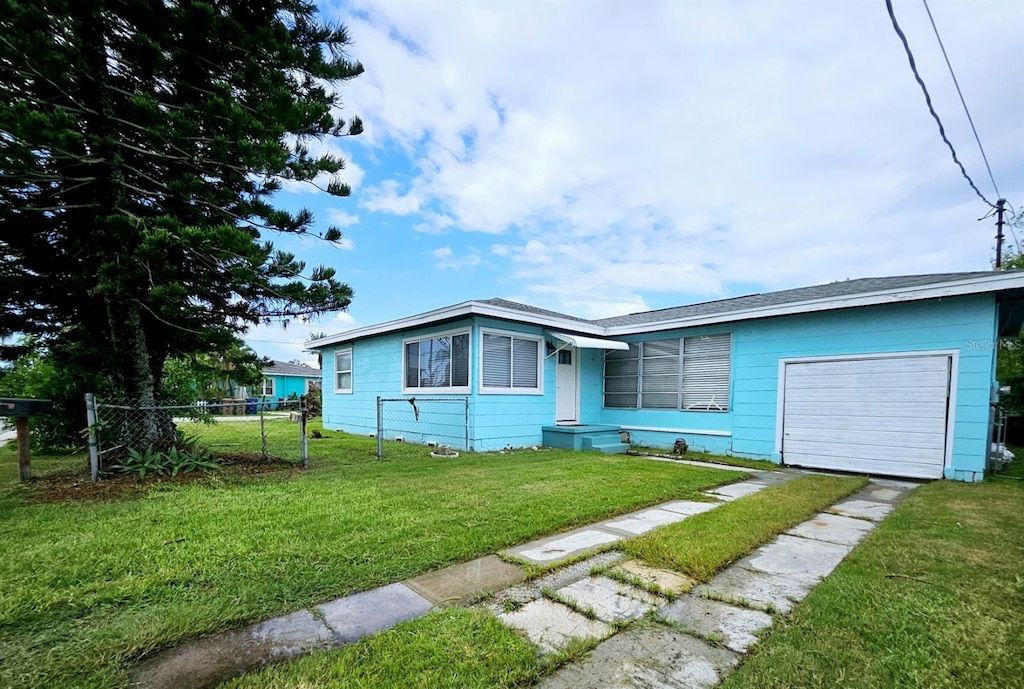 view of front of property featuring an attached garage, a front yard, fence, and driveway