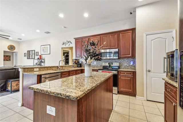 1939 Heartland Cir, Valrico, FL 33594 - kitchen featuring a peninsula, light stone countertops, a sink, appliances with stainless steel finishes, and light tile patterned floors