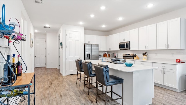 5735 Mezzana Run, Palmetto, FL 34221 - kitchen featuring stainless steel appliances, a breakfast bar, light countertops, light wood-style floors, and white cabinetry