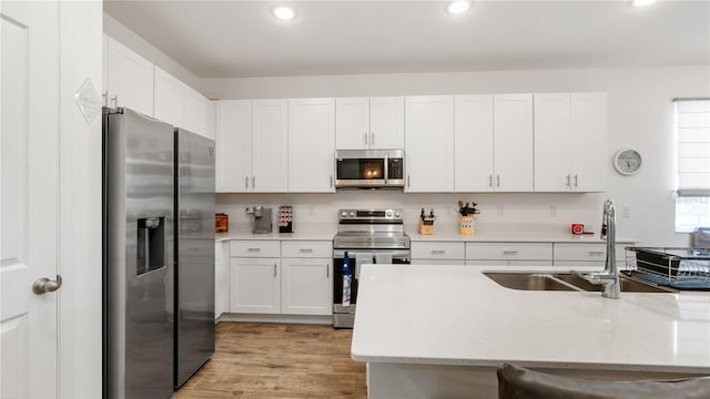 5735 Mezzana Run, Palmetto, FL 34221 - kitchen with white cabinetry, light wood-style flooring, stainless steel appliances, and a sink