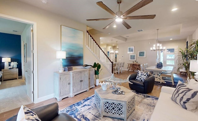 living area with baseboards, visible vents, recessed lighting, ceiling fan with notable chandelier, and stairway