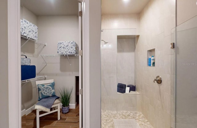full bathroom with a walk in closet, wood finished floors, and a stall shower
