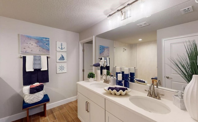 bathroom featuring wood finished floors, visible vents, baseboards, and a sink