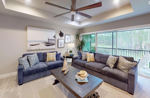 living room with a tray ceiling, carpet floors, a ceiling fan, and recessed lighting