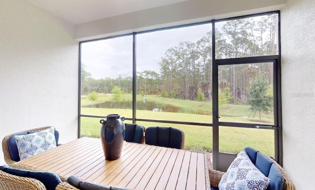 sunroom / solarium with outdoor dining space and a water view