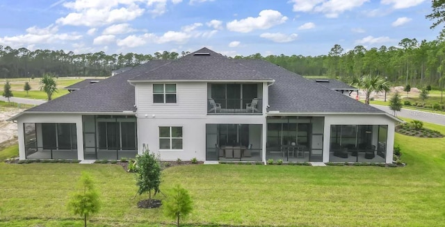 back of house featuring a shingled roof, a sunroom, and a yard