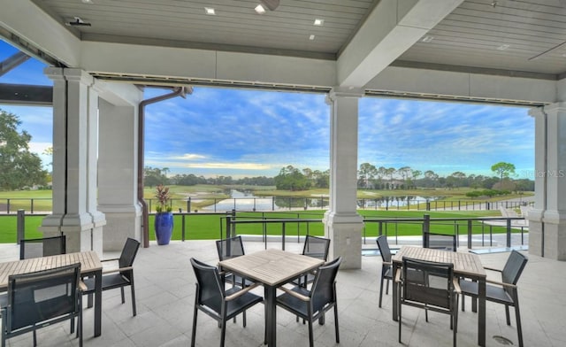 view of patio with view of golf course, outdoor dining space, and a water view