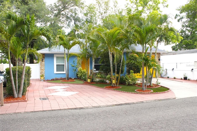 view of front facade featuring fence, stucco siding, and concrete driveway