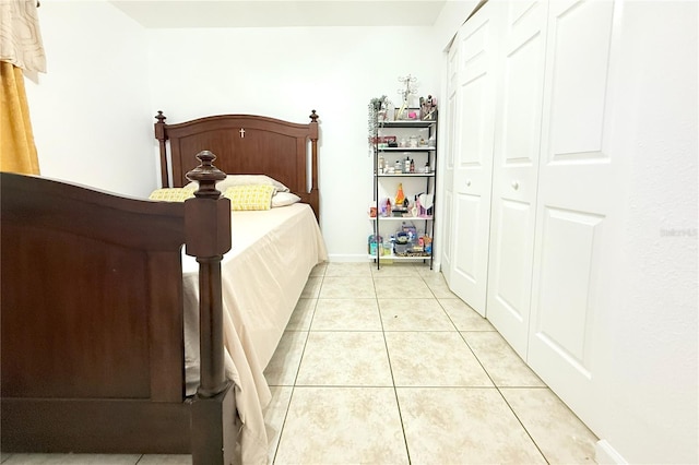 bedroom with baseboards, light tile patterned floors, and a closet
