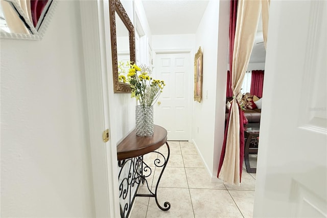 hall featuring baseboards and light tile patterned floors