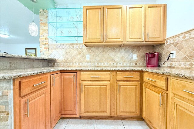 kitchen featuring light stone counters, pendant lighting, light tile patterned floors, and backsplash