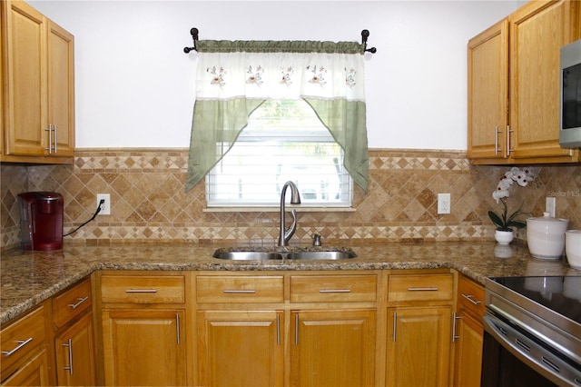 kitchen featuring a sink, appliances with stainless steel finishes, stone countertops, and backsplash