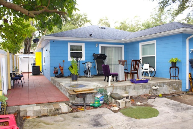 back of property with central AC, a patio area, roof with shingles, and fence