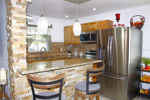 3306 E Chelsea St, Tampa, FL 33610 - kitchen with brown cabinets, light stone counters, a sink, stainless steel appliances, and a peninsula