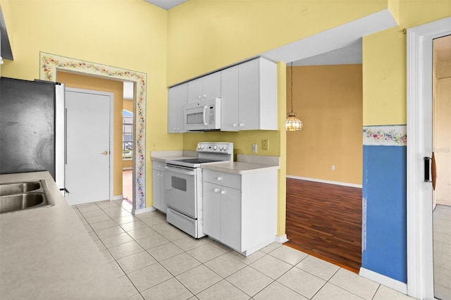 1046 Almondwood Dr, Trinity, FL 34655 - kitchen with white cabinets, light countertops, baseboards, light tile patterned flooring, and white appliances