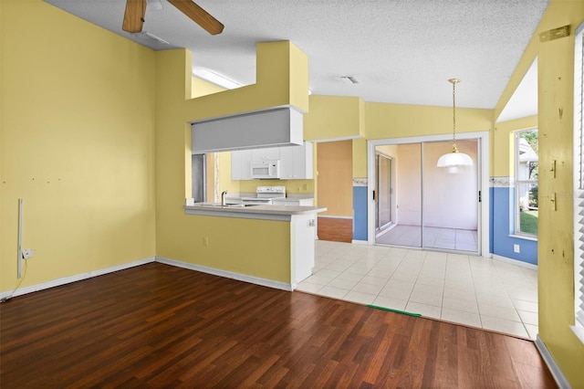 1046 Almondwood Dr, Trinity, FL 34655 - kitchen with lofted ceiling, visible vents, wood finished floors, white appliances, and a peninsula