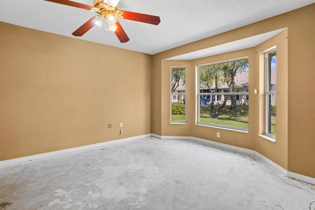 1046 Almondwood Dr, Trinity, FL 34655 - empty room featuring a textured ceiling, unfinished concrete floors, ceiling fan, and baseboards
