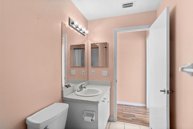 1046 Almondwood Dr, Trinity, FL 34655 - half bath featuring a textured ceiling, visible vents, toilet, vanity, and tile patterned flooring