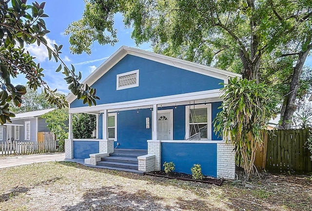 bungalow with fence, a porch, and brick siding