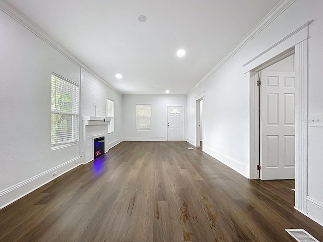 unfurnished living room featuring ornamental molding, a glass covered fireplace, visible vents, and dark wood finished floors