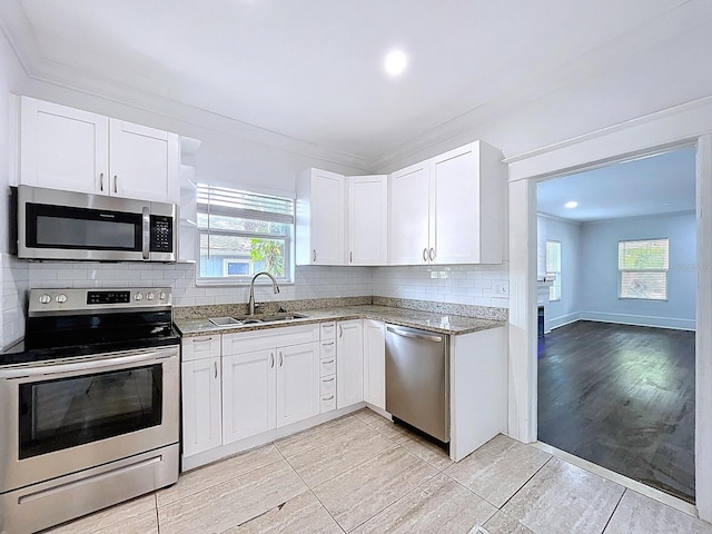 kitchen featuring a healthy amount of sunlight, stainless steel appliances, light stone countertops, and a sink
