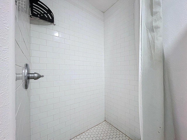 bathroom featuring tiled shower and a textured wall